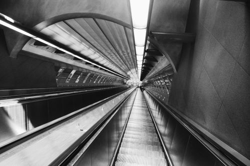 Free Dramatic black and white image of a modern subway escalator highlighting urban architecture. Stock Photo