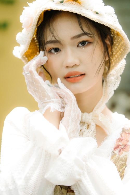 Free Graceful woman wearing vintage lace with a floral hat, exuding classic charm. Stock Photo