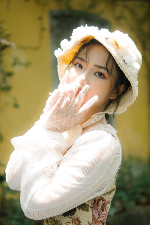 Free Charming portrait of a woman in lace gloves and floral hat, exuding elegance and grace. Stock Photo