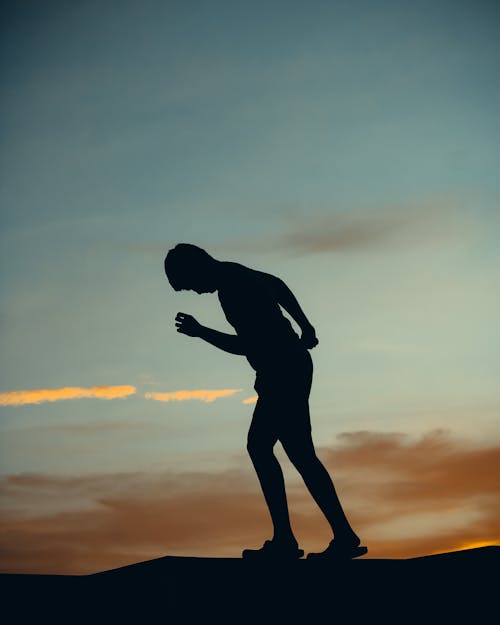 Silhouette of Man Walking During Sunset