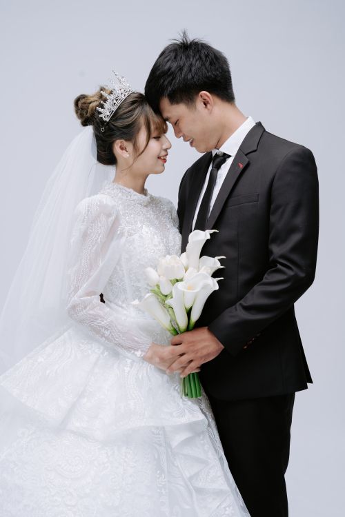 Free A newlywed couple in a loving pose capturing their wedding day bliss in a studio setting. Stock Photo
