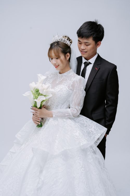 Free Elegant wedding portrait of a smiling bride and groom embracing with bouquet. Stock Photo