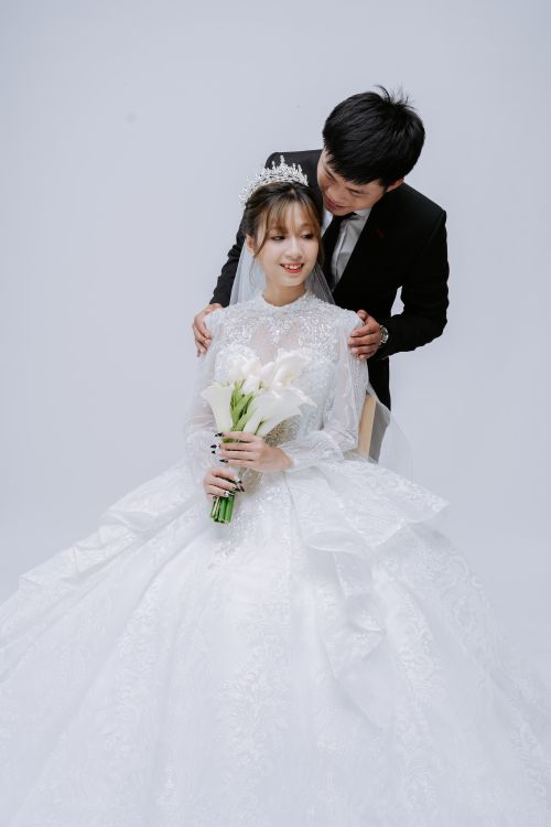 Free Beautiful Asian couple posing in a studio in wedding attire, showcasing elegance and love. Stock Photo