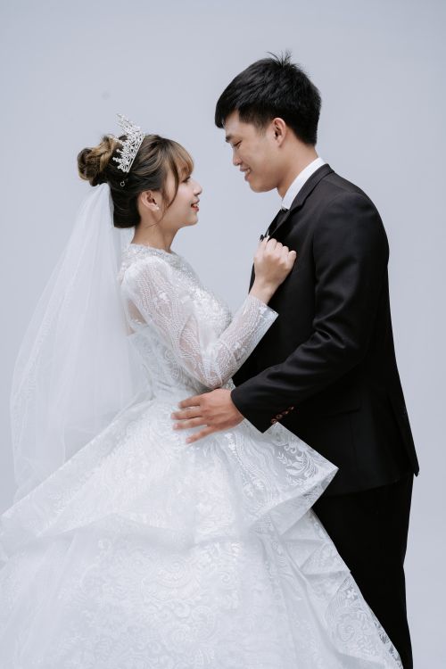 Free A joyful bride and groom share a tender moment in a studio setting, showcasing love and elegance. Stock Photo