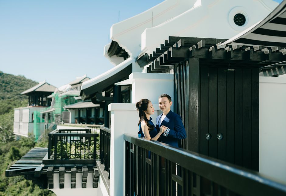 Casal elegante se abraçando em varanda luxuosa com vista panorâmica na Europa, transmitindo romance e exclusividade.