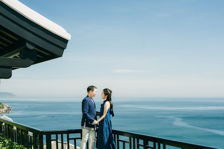 Couple Standing On Balcony With Ocean View