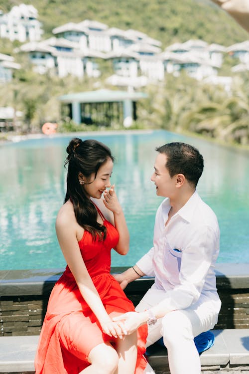 Man and Woman Sitting Together near Swimming Pool