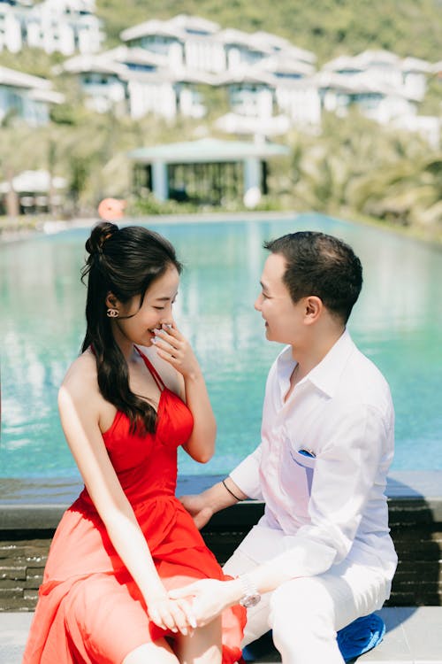 Photograph of a Man and a Woman Sitting Near a Swimming Pool