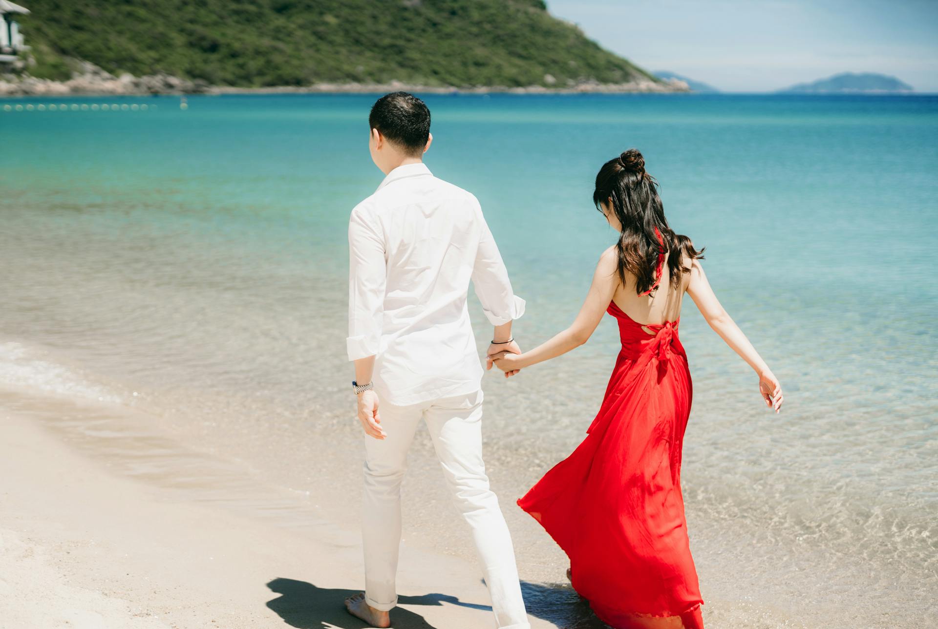 A couple holding hands walking along a scenic beach, perfect for travel and romance themes.