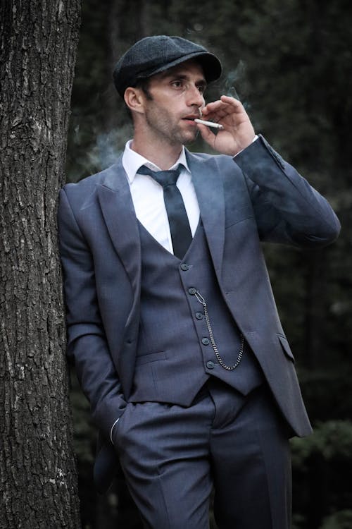 Man Smoking a Cigarette while Leaning on a Tree