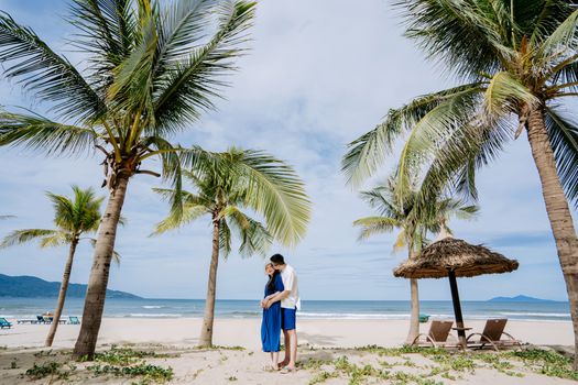 Couple in love embracing among palm trees on a beautiful tropical beach.