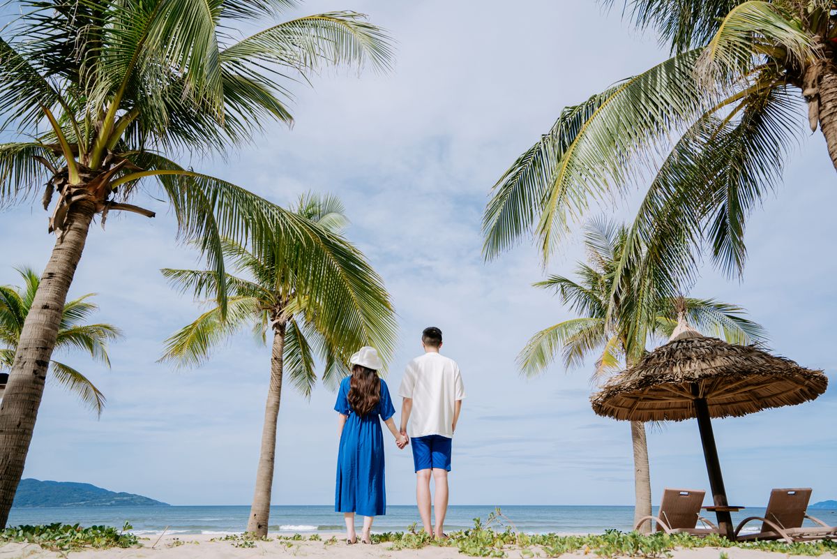 Dos personas de la mano en una playa tropical