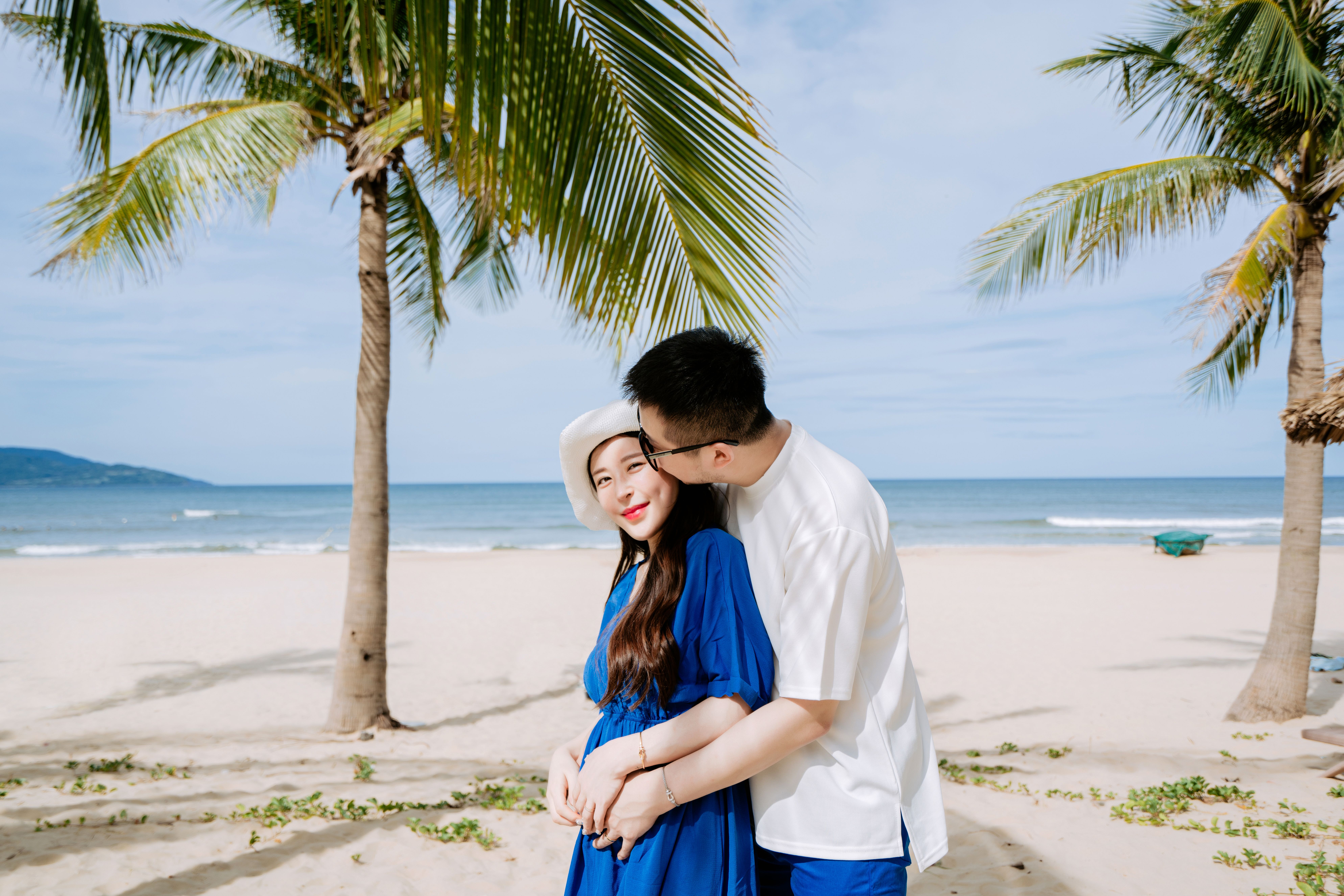 A loving couple embraces on a tropical beach, showcasing affection and scenery.