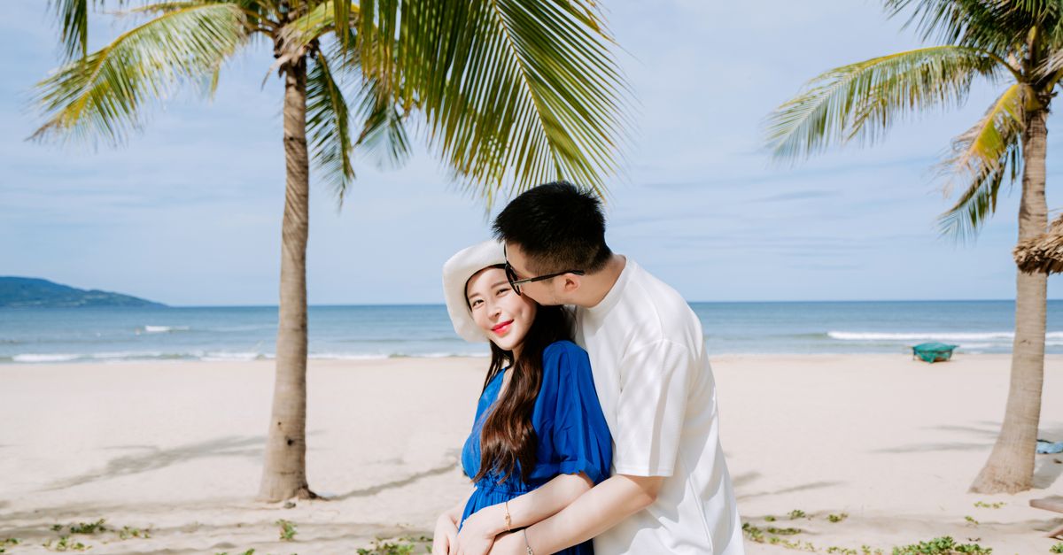 A loving couple embraces on a tropical beach, showcasing affection and scenery.