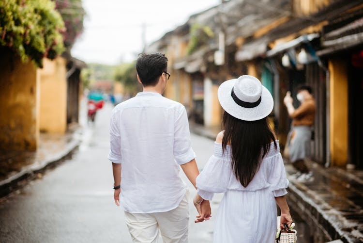 Backs Of A Man And A Woman Walking Down The Street Holding Hands