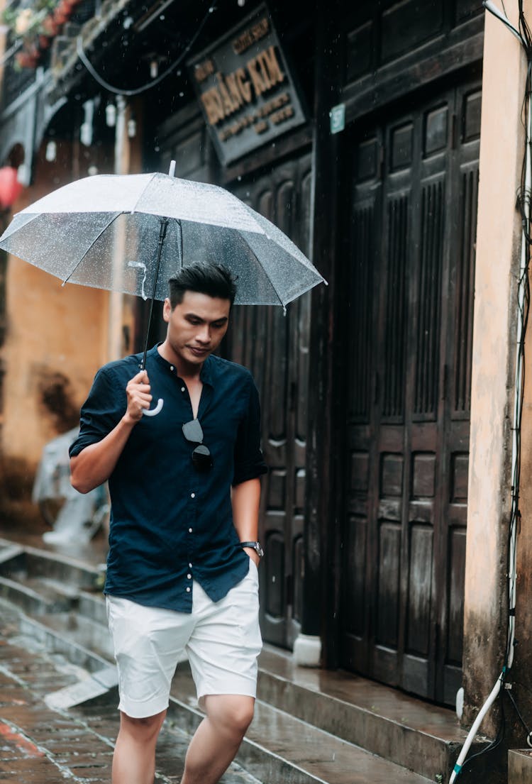 A Man Holding An Umbrella While Walking