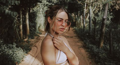 Free Portrait of a stylish woman in a forest pathway wearing sunglasses and summer attire. Stock Photo