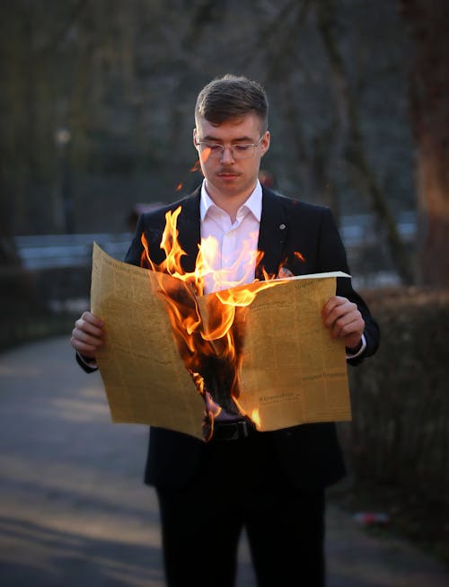 Free A Man Holding Burning Newspaper Stock Photo