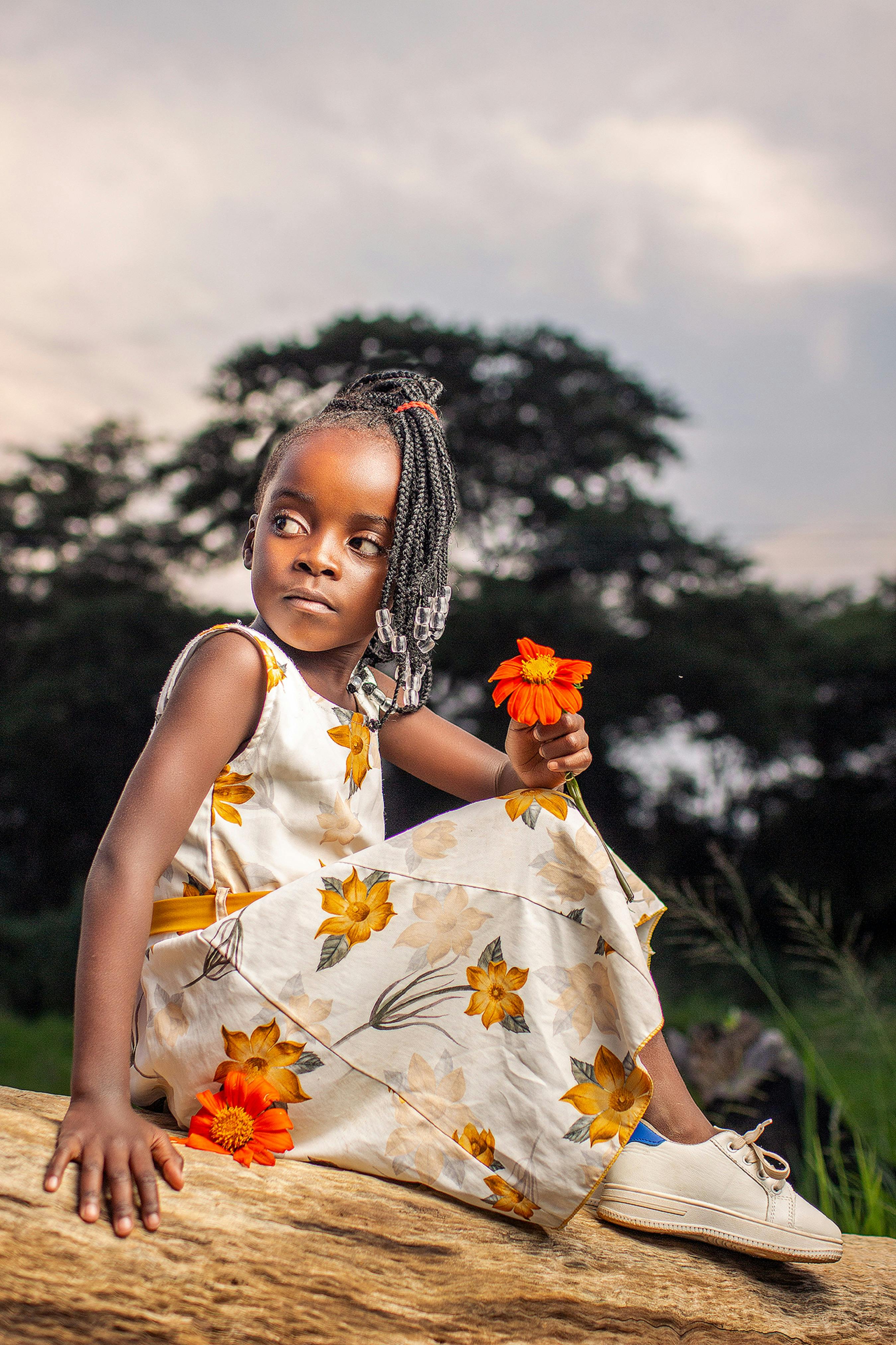 photo of a child in a floral dress holding a flower