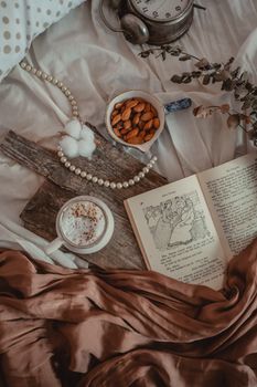 Relaxing still life with coffee, almonds, and an open book on a cozy bed in Turkey.
