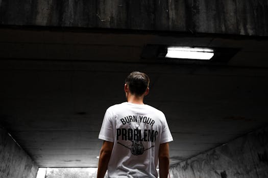 A man stands in an urban tunnel wearing a t-shirt with a bold statement.