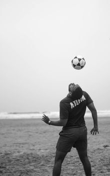 Athlete performing soccer tricks at the beach in a dynamic black and white composition.