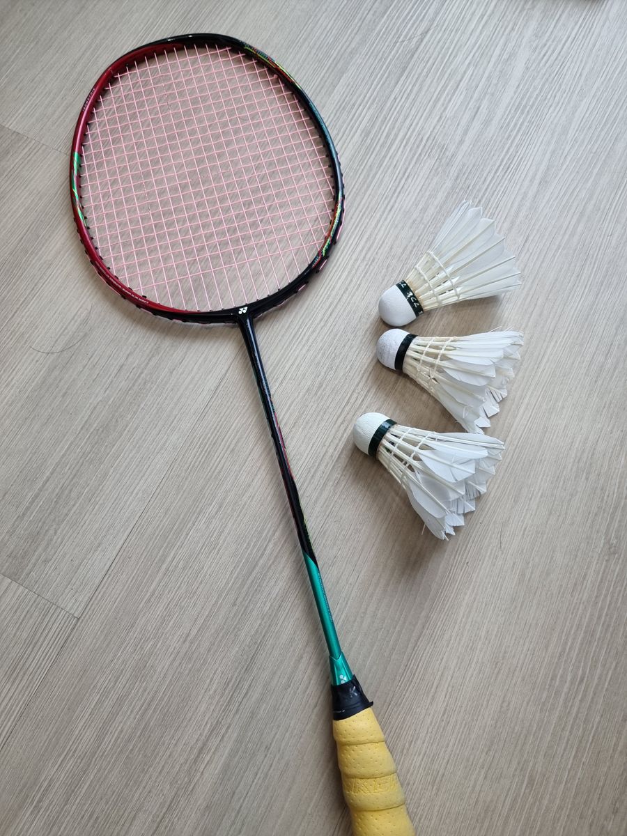 Raqueta y volantes de bádminton sobre piso de madera