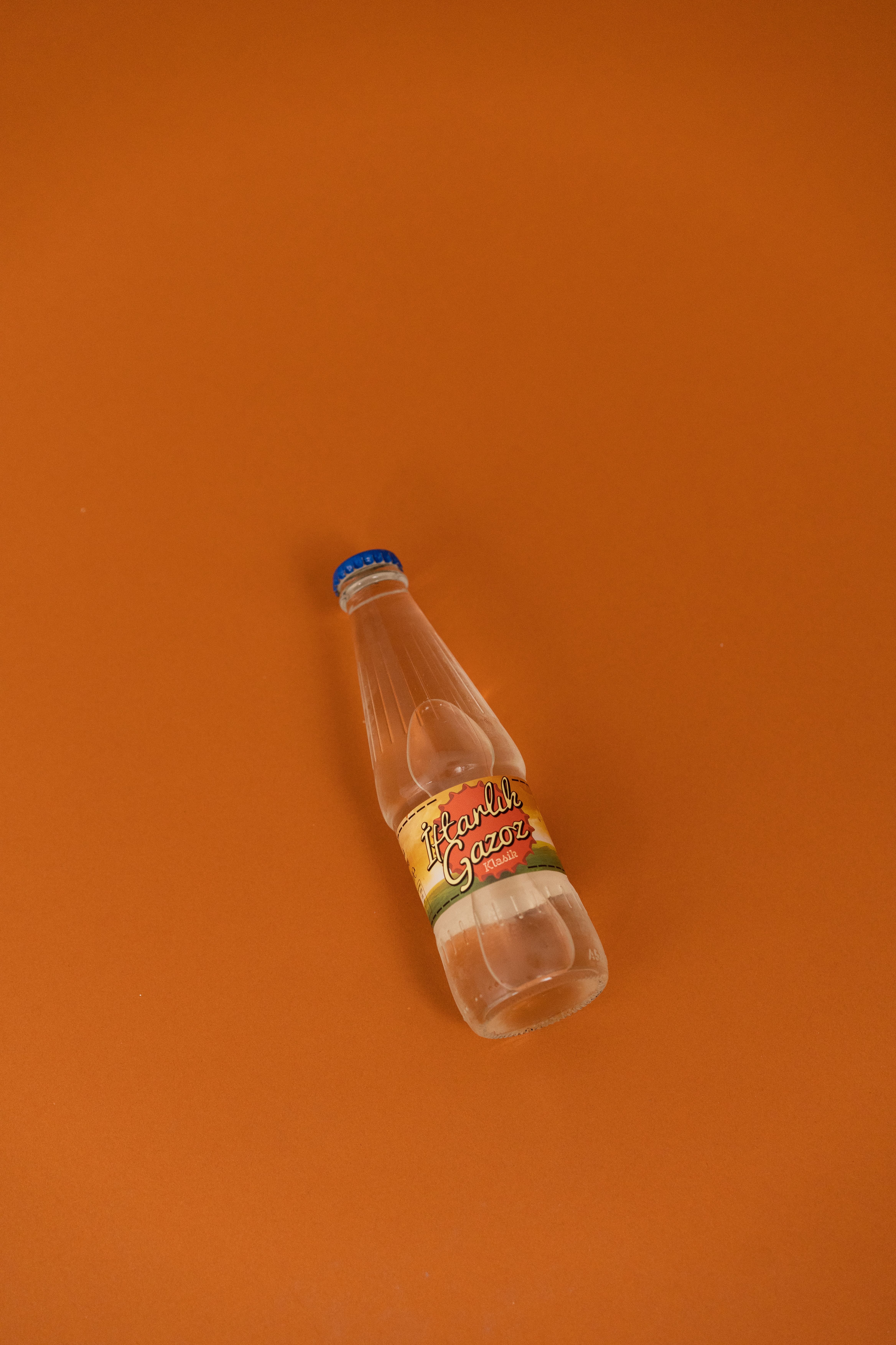 A vintage soda bottle lying on an orange background in a minimalist style.