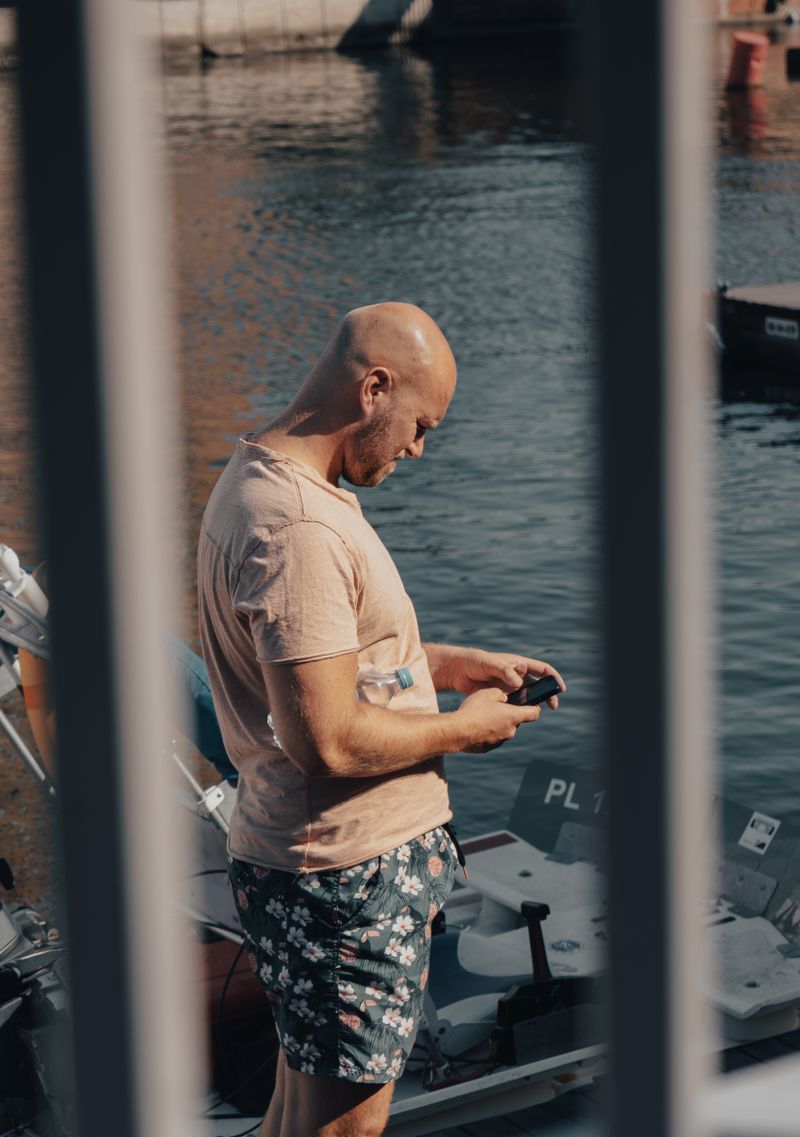 Placeholder: a captain checking his phone dockside