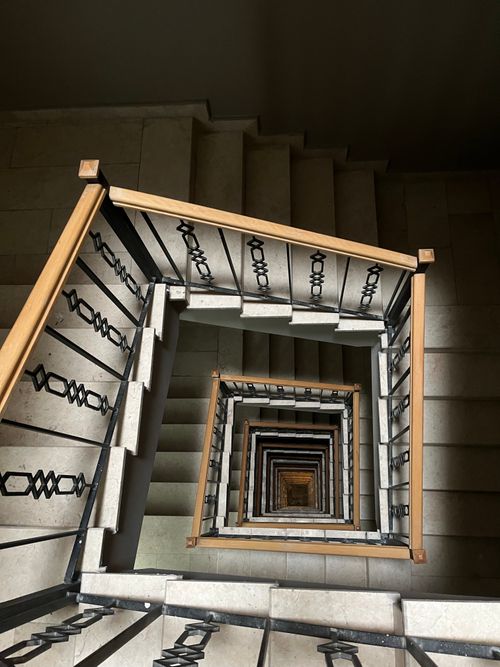Free Top view of a spiral staircase featuring intricate iron railings and wooden handrails indoors. Stock Photo