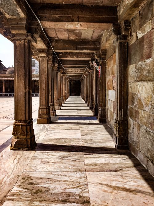 Free A narrow, empty stone corridor with pillars in Ahmedabad, India, showcasing ancient architecture. Stock Photo