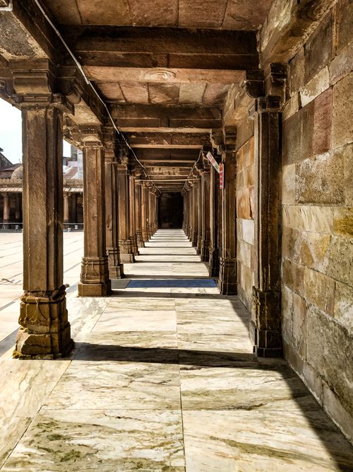 Free Sunlit ancient corridor with stone pillars in Ahmedabad, India, showcasing historical architecture. Stock Photo