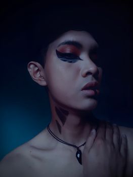 Close-up portrait of a person with bold, artistic eye makeup and facial paint.