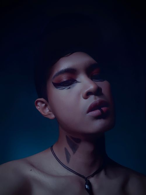 Free Close-up portrait of a person with artistic face paint and necklace, exuding a mysterious vibe. Stock Photo
