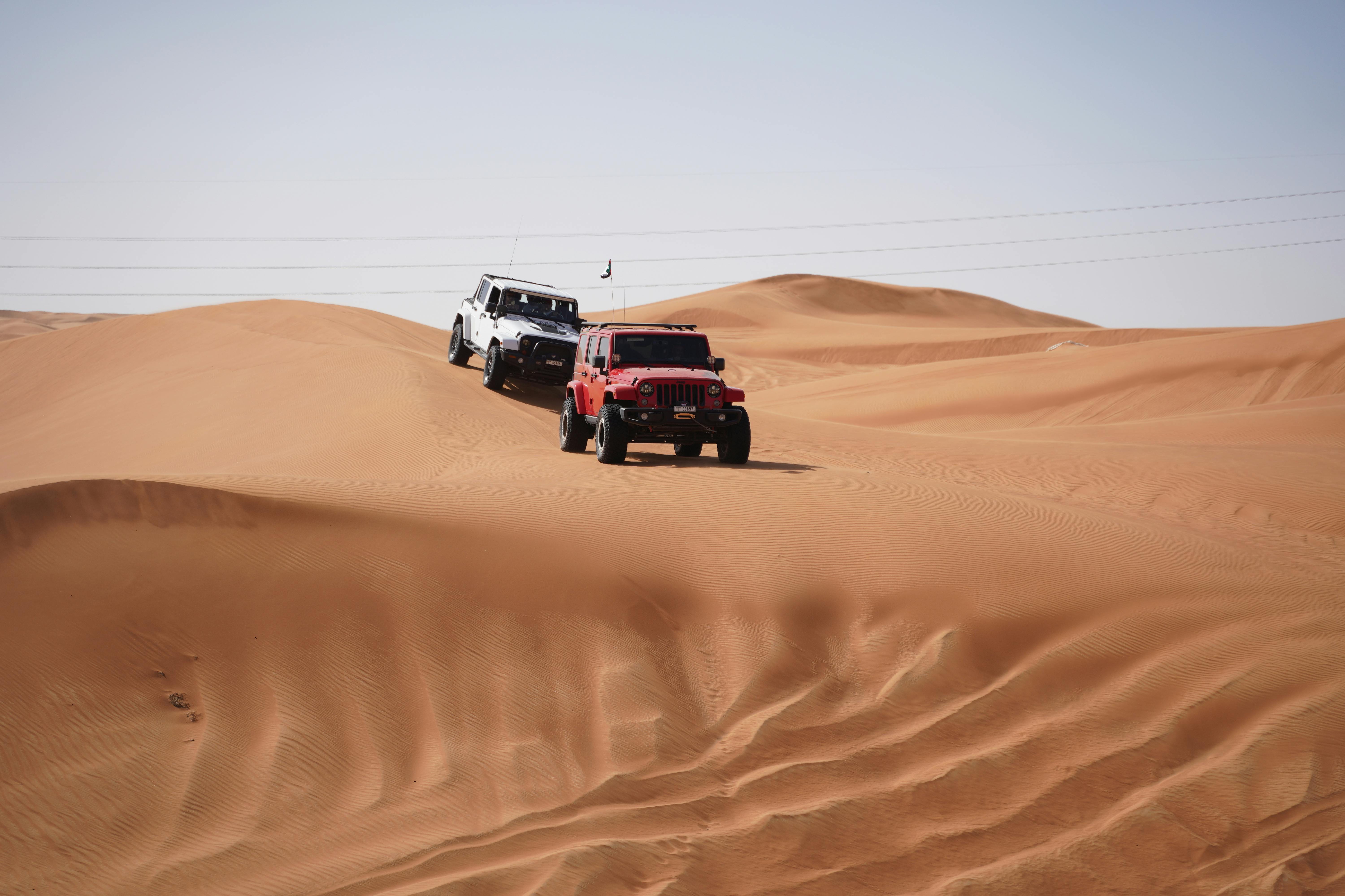 Two jeeps traverse the sandy dunes showcasing a thrilling desert adventure.