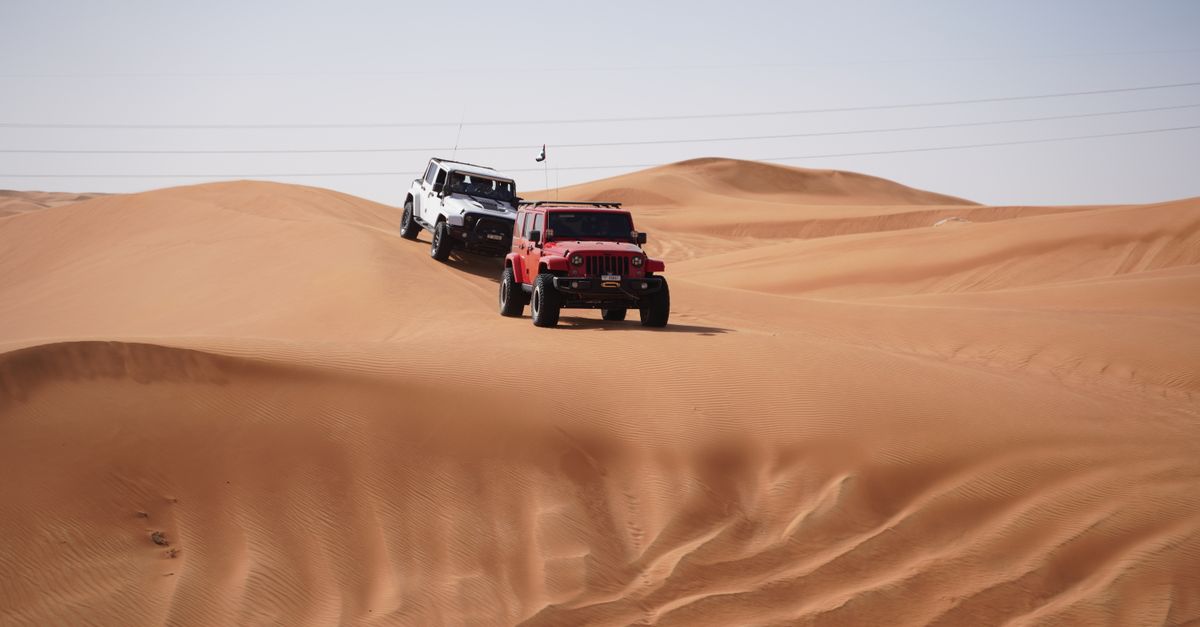 Two jeeps traverse the sandy dunes showcasing a thrilling desert adventure.