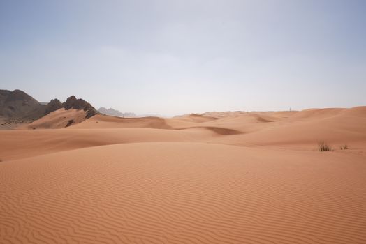 A breathtaking view of sand dunes in a vast desert under a bright sky.