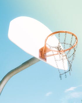 Close-up of a basketball hoop with chain net against a bright sky, symbolizing sports and outdoor activity.