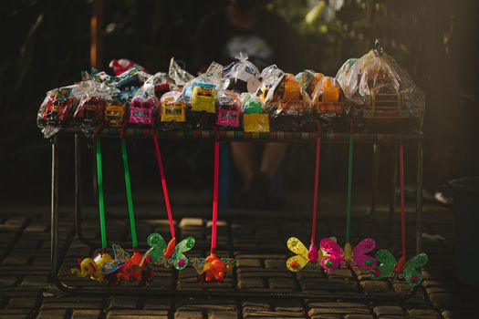 A vibrant street display of various colorful toys packaged and arranged on a market stall.