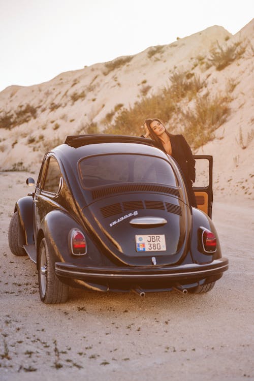 A Woman Standing by a Vintage Car in a Desert