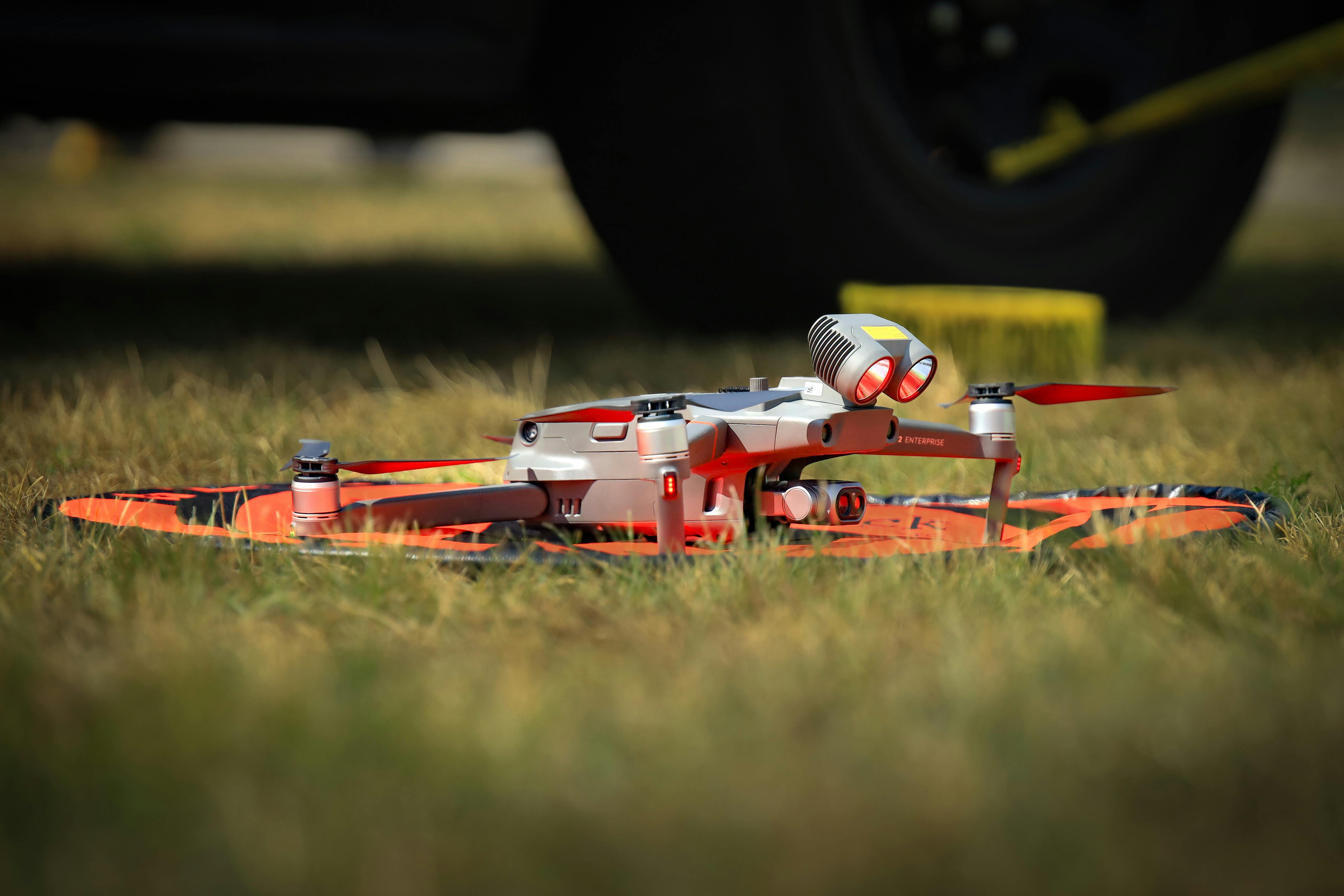 Close-up of a high-tech drone resting on a grass landing pad, ready for action.