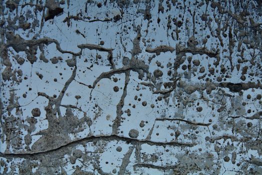 Abstract capture of a textured concrete surface with cracks and stains, ideal for backgrounds and creative designs.