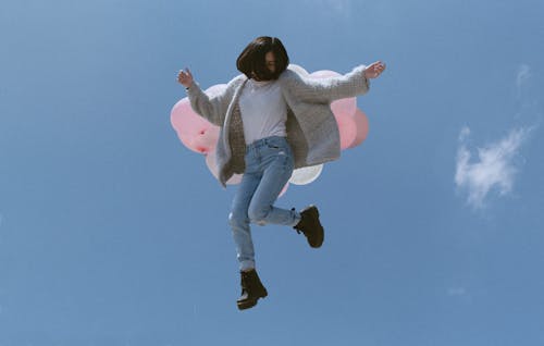 Girl with Pink Balloons Jumping in Sky