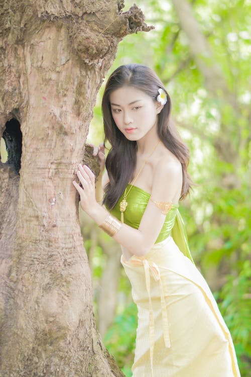 Woman in Yellow Green Tube Top and Yellow Skirt Leaning on Brown Tree