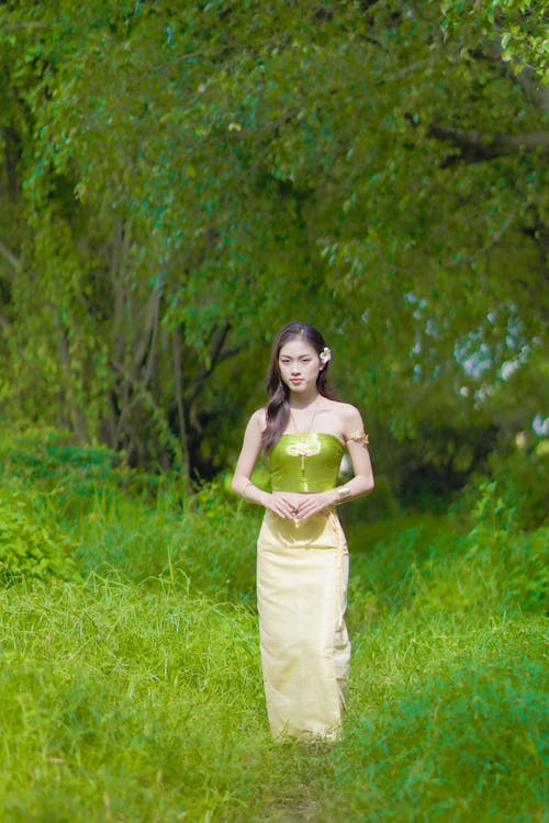 Woman in a Green Top Standing on a Grass Field