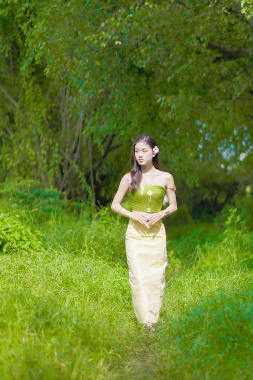 Woman in a Green Top Walking on the Grass