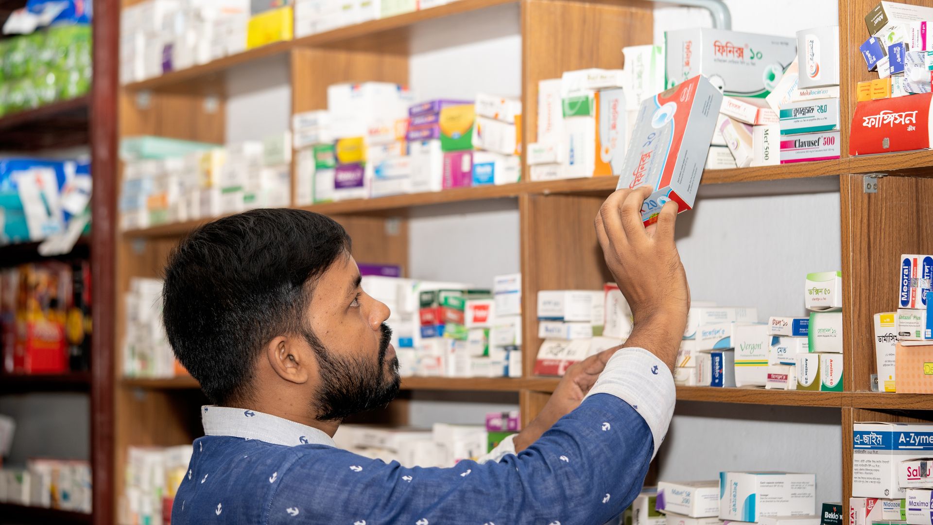 Buy Modafinil Online Without a Prescription: Is It Safe? A pharmacist organizing medication on shelves in a pharmacy in Bangladesh.