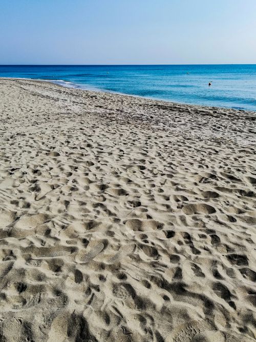 Free Peaceful sandy seashore under a clear blue sky, perfect for a summer vacation. Stock Photo