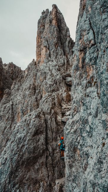 Fotomural Escalador en solitario navegando por un desafiante acantilado rocoso en medio de un paisaje montañoso accidentado.