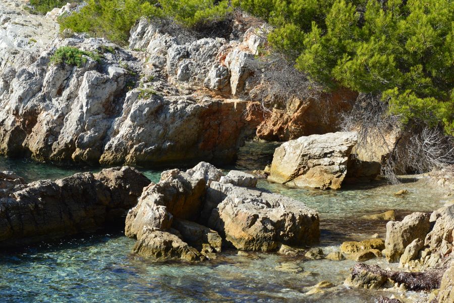 Explore a scenic rocky coastline with clear water and lush greenery. Perfect for nature lovers.